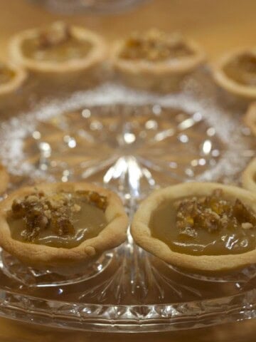 Glass platter of caramel tarts decorated with walnut praline