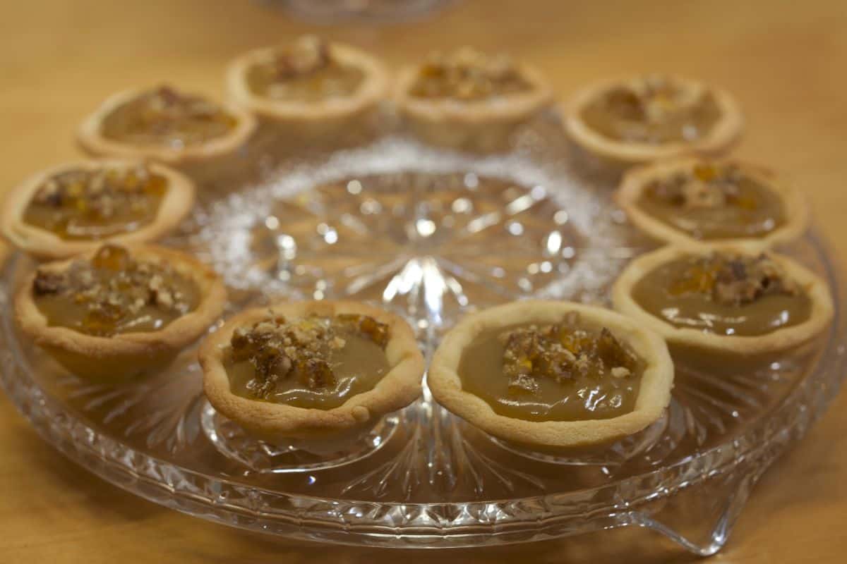 Glass platter of caramel tarts decorated with walnut praline